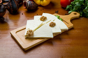 Suluguni cheese sliced on a plate on wooden table - 555260271