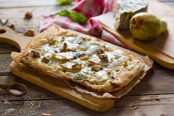 pizza with pear and Gorgonzola on Roman dough, pinsa on wooden table - 555260479