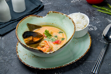 Tom Yam soup with shrimps and mussels on dark table