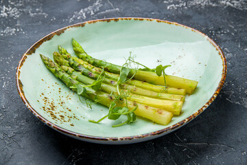 Asparagus grill on plate on dark table