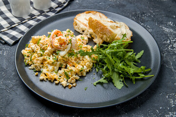 scramble with shrimp and aragula on dark plate