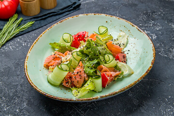 mixed salad with salmon and tomatoes on dark table