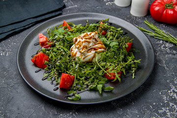 Salad with buratta cheese and tomatoes with aragula on dark table
