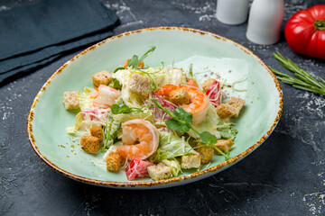salad caesar with shrimps on plate on dark table