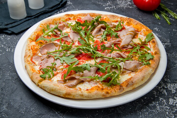 Obraz na płótnie Canvas Italian meat pizza with roastbeef and aragula on a dark table
