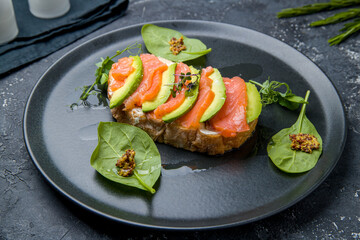 bruschetta with salmon and avocado with cheese on black plate