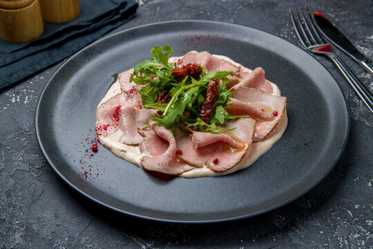 vitello tonato on a black plate on dark table