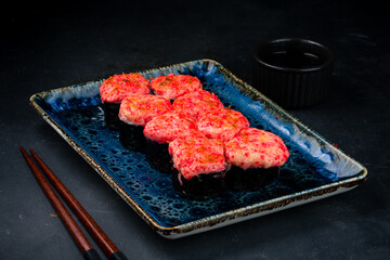 Set of hot maki sushi rolls with tuna tartare, cream cheese, avocado, red flying fish caviar and soy sauce.