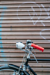 Cropped image of a vintage classic bicycle leaning against the closing shutter of a shop.