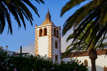 Fototapeta na wymiar Bell tower of the church of Saint Mary of Betancuria surrounded by palm trees in the former capital city of Fuerteventura island in the Canaries, Spain