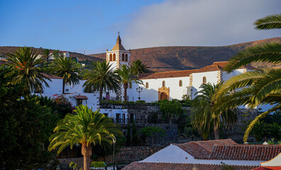Panoramic wide view of the church of Saint Mary of Betancuria surrounded by palm trees at sunset in the former capital city of Fuerteventura island in the Canaries, Spain