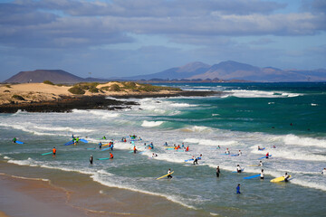 Moro beach in the Corralejo Natural Park in the north of Fuerteventura island in the Canaries, Spain - Crowd of surfers waiting for a wave in the Atlantic Ocean