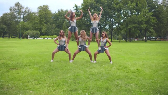 Cheerleaders doing pyramid stunt outdoors. Realtime