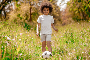 Curly-haired boy in white sportswear playing football