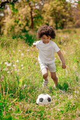 Obraz premium Curly-haired boy in white sportswear playing football