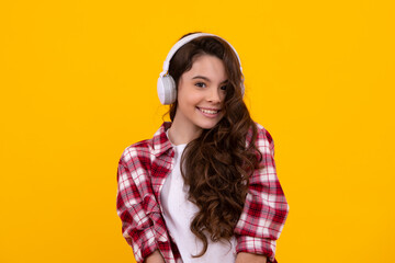 Teen girl in headphones listen to music. Wireless headset device accessory. Child enjoys the music in earphones on yellow background. Happy casual teenager.
