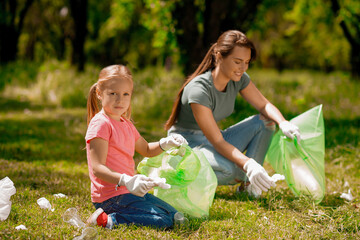 Young woman and her child collecting gargabe in the park