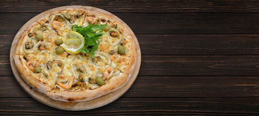 Pizza with seafood, olives and cheese, on a wooden board. Banner