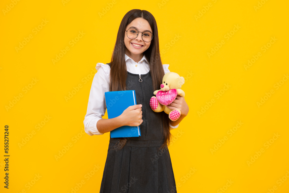 Wall mural School girl hold toy. School children with favorite toys on yellow isolated background. Childhood concept. Happy school girl, positive and smiling emotions.