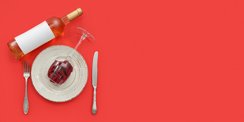 Table setting for Valentine's Day with rose and bottle of wine on red background with space for text