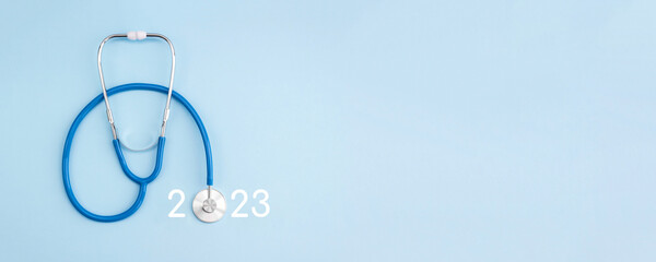 Stethoscope and numbers 2023 on light blue background. Concept of health care in the New Year....