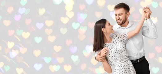 Happy young couple dancing against light background with space for text