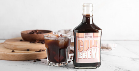 Bottle and glass of tasty cold brew on light background