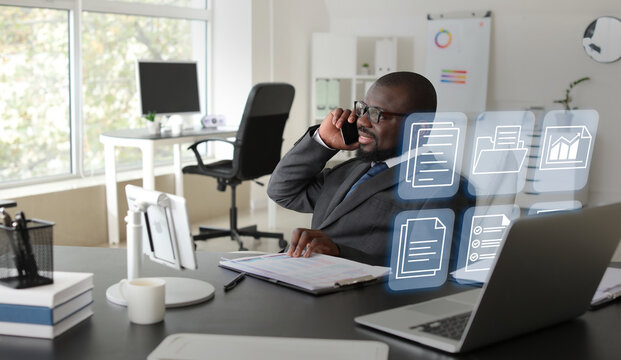 African-American businessman talking by mobile phone and digital files in office