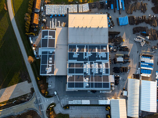 Factory building producing plastic pipes with large array of solar panels on the roof at sunset top down