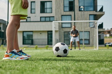 Close up of unrecognizable boy playing football with father standing in gates and scoring goal, copy space