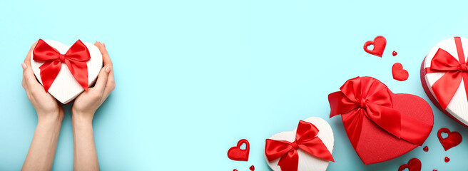 Female hands and heart-shaped gift boxes on light blue background. Banner for Valentine's Day