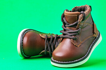 Leather children's boots with laces on green background. Modern leather children's shoes.