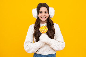 Funny child with lollipop over yellow isolated background. Sweet childhood life. Teen girl with...
