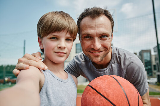 POV of father and son taking selfie in basketball court and enjoying sports together