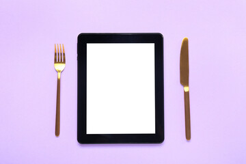 Tablet computer and cutlery on color background