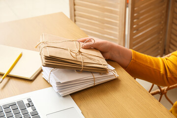 Woman holding stack of tied letters on wooden table. Mail concept