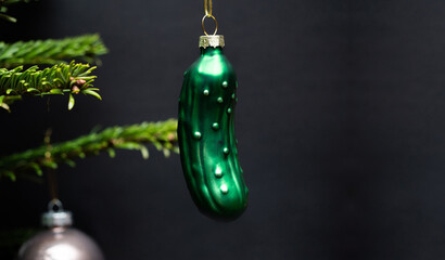 Christmas tree decorations. A green glass cucumber is hanging on a christmas tree. Green branches...