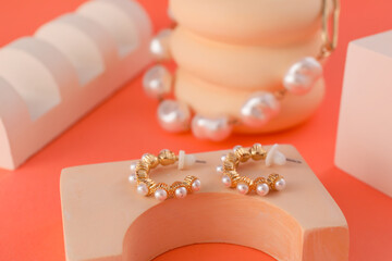 Stands with stylish pearl earrings and bracelet on color background
