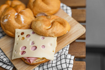 Delicious kaiser rolls with ham and cheese on wooden board