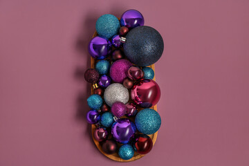 Wooden board with beautiful Christmas balls on color background