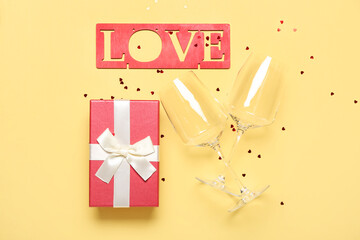 Word LOVE, gift, glasses and hearts on yellow background. Valentine's Day celebration