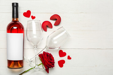 Fototapeta na wymiar Bottle of wine, glasses, rose and cookies on white wooden background. Valentine's Day celebration