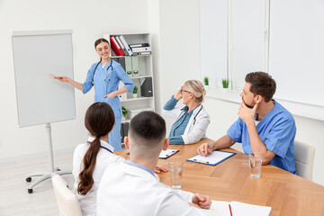 Doctor giving lecture near flipchart in conference room