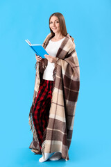 Young woman with plaid reading book on blue background