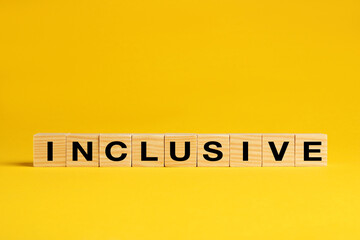 Wooden cubes with word Inclusive on yellow background. Space for text