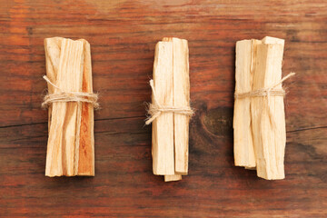 Bunches of tied Palo Santo sticks on wooden table, flat lay