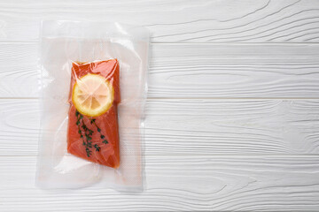Vacuum pack of salmon on white wooden table, top view. Space for text