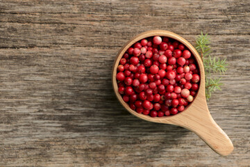 Cup with tasty ripe lingonberries and spruce twig on wooden surface, flat lay. Space for text
