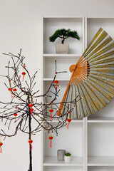 Glowing tree lamp, shelving unit with decor for Chinese New Year celebration in room