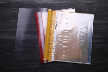 File folders with punched pockets on black wooden table, flat lay